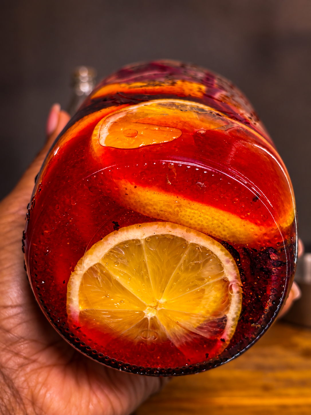 Bottom view of a mason jar showing lemon and orange slices in ruby vinegar