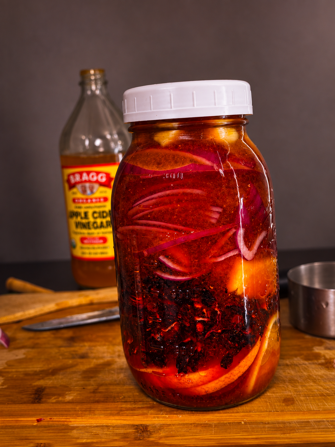 Hibiscus fire cider infusing in a mason jar with citrus, onion, and roselle