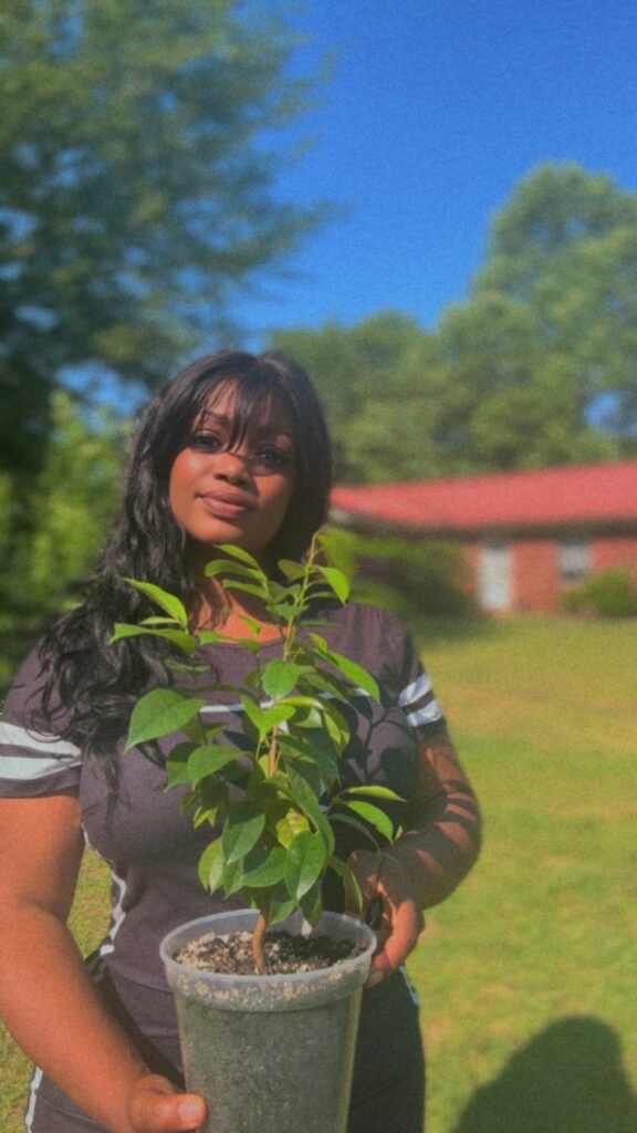 Allyse holding a young plant outdoors